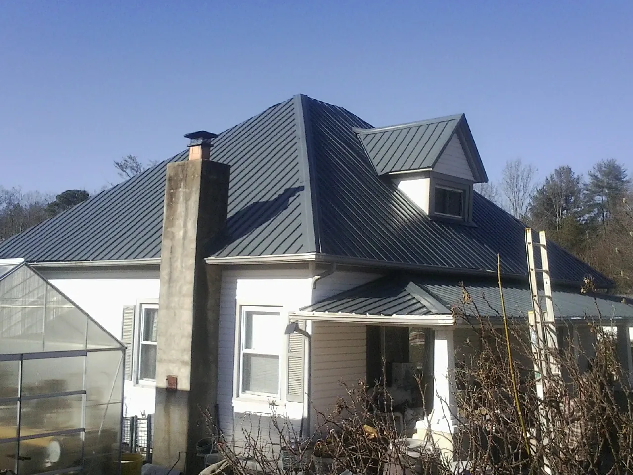 Dark blue standing seam metal roof on a white farmhouse with dormer — Slate & Tile Roof Repair by Roofing Brothers in Lansdale