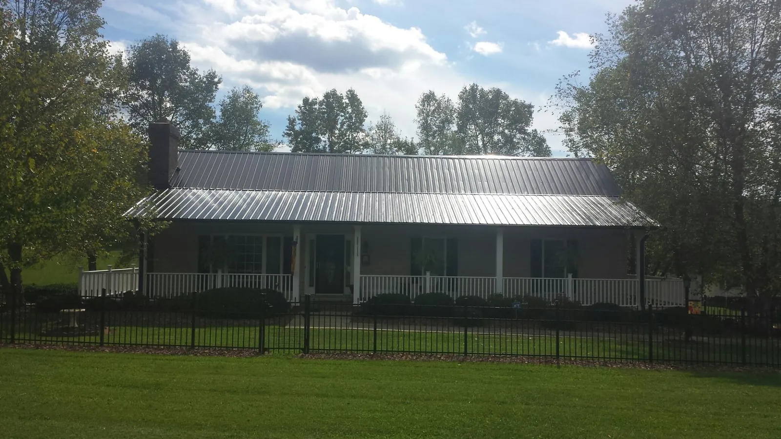 Gray metal roof on a brick ranch with a full width front porch — Gutter Guard Installation work by our crew in Lansdale