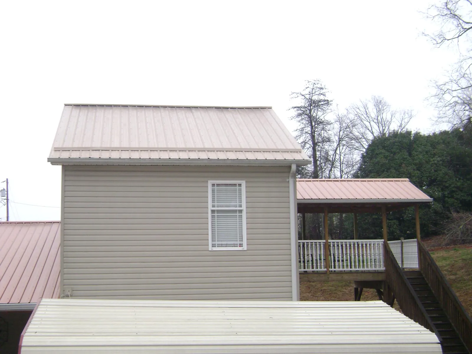 Tan metal roofs on a two story addition and attached porch, from a Roof Replacement job in Lansdale