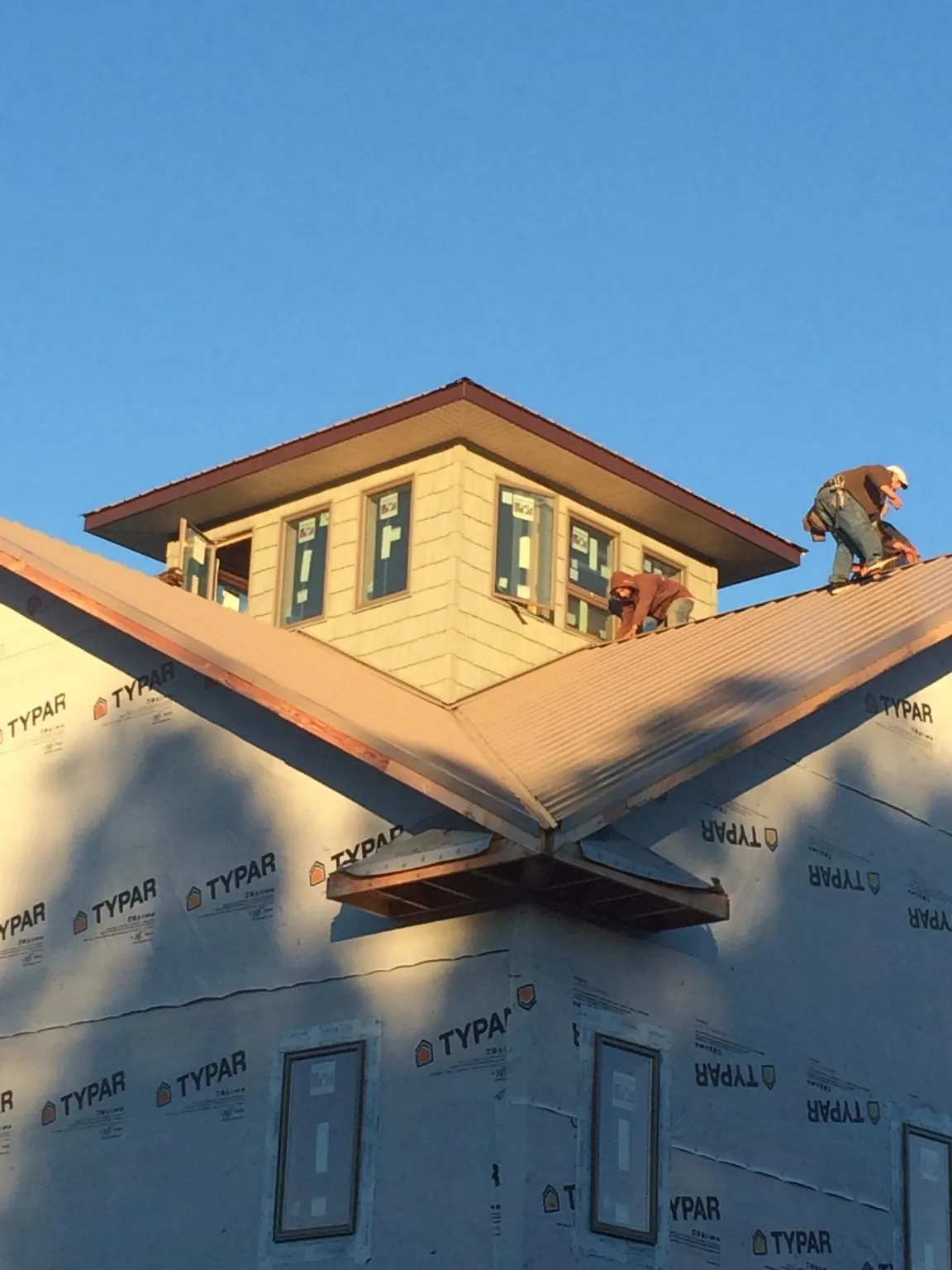 Roofers working around a rooftop cupola on a new metal roof at sunset — Roof Waterproofing in Lansdale by Roofing Brothers